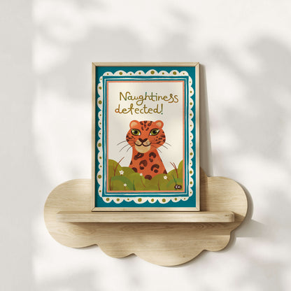 Framed artwork with a cheeky leopard and text 'Naughtiness detected!' on a white wall.