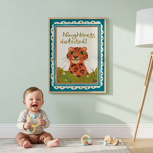 A leopard illustration with a cheeky smile. Naughtiness Detected written on the print. A baby is sitting in front of it. 
